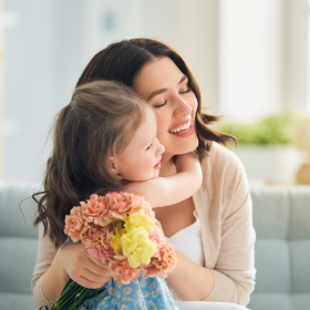 Maman et sa fille se font un câlin en tenant de fleurs